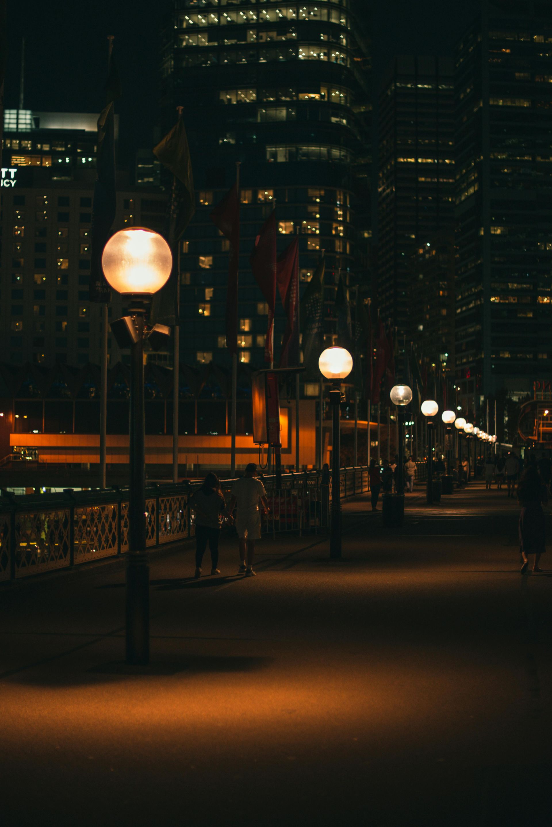 A row of street lights are lit up at night in a city.
