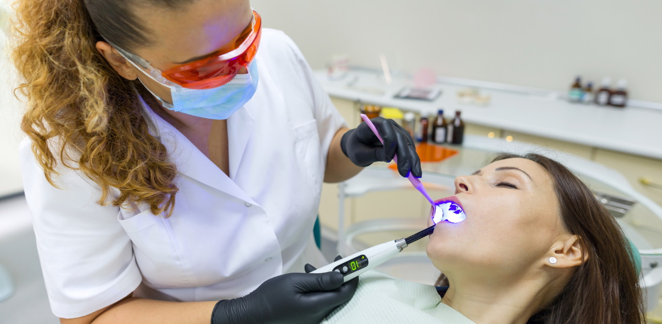 a woman is getting her teeth whitened by a dentist in a dental office .