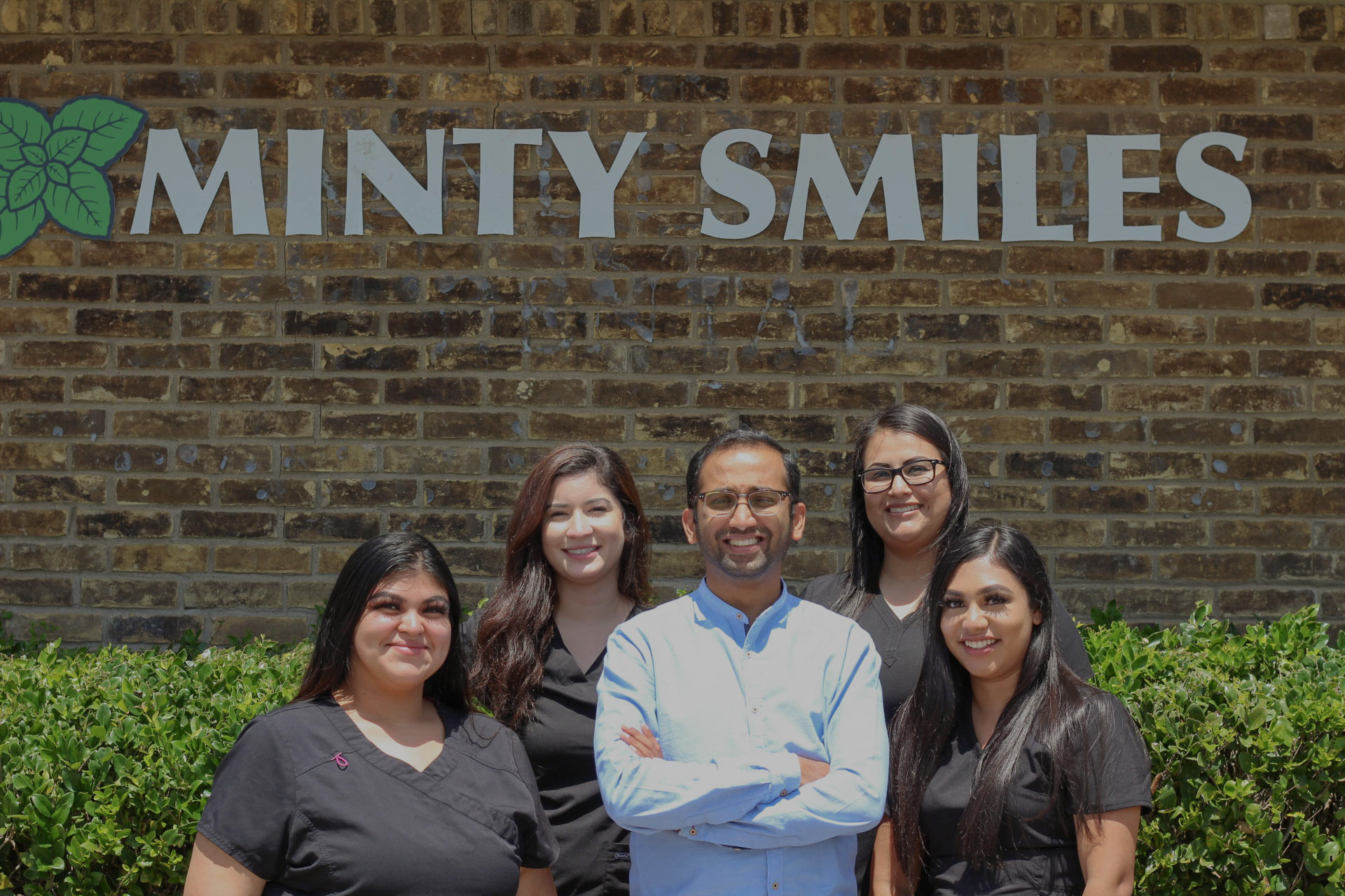 a group of people are posing for a picture in front of a minty smiles sign .