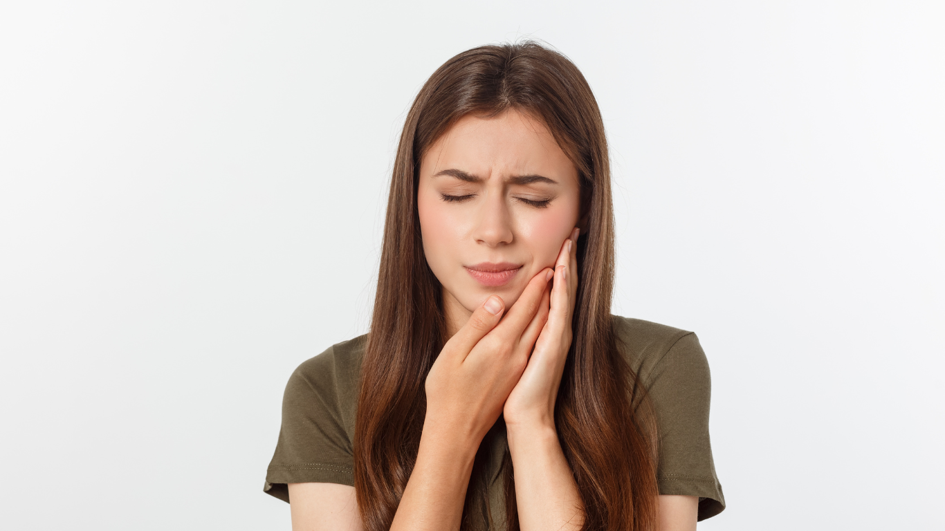 a woman is holding her face in pain because of a toothache .
