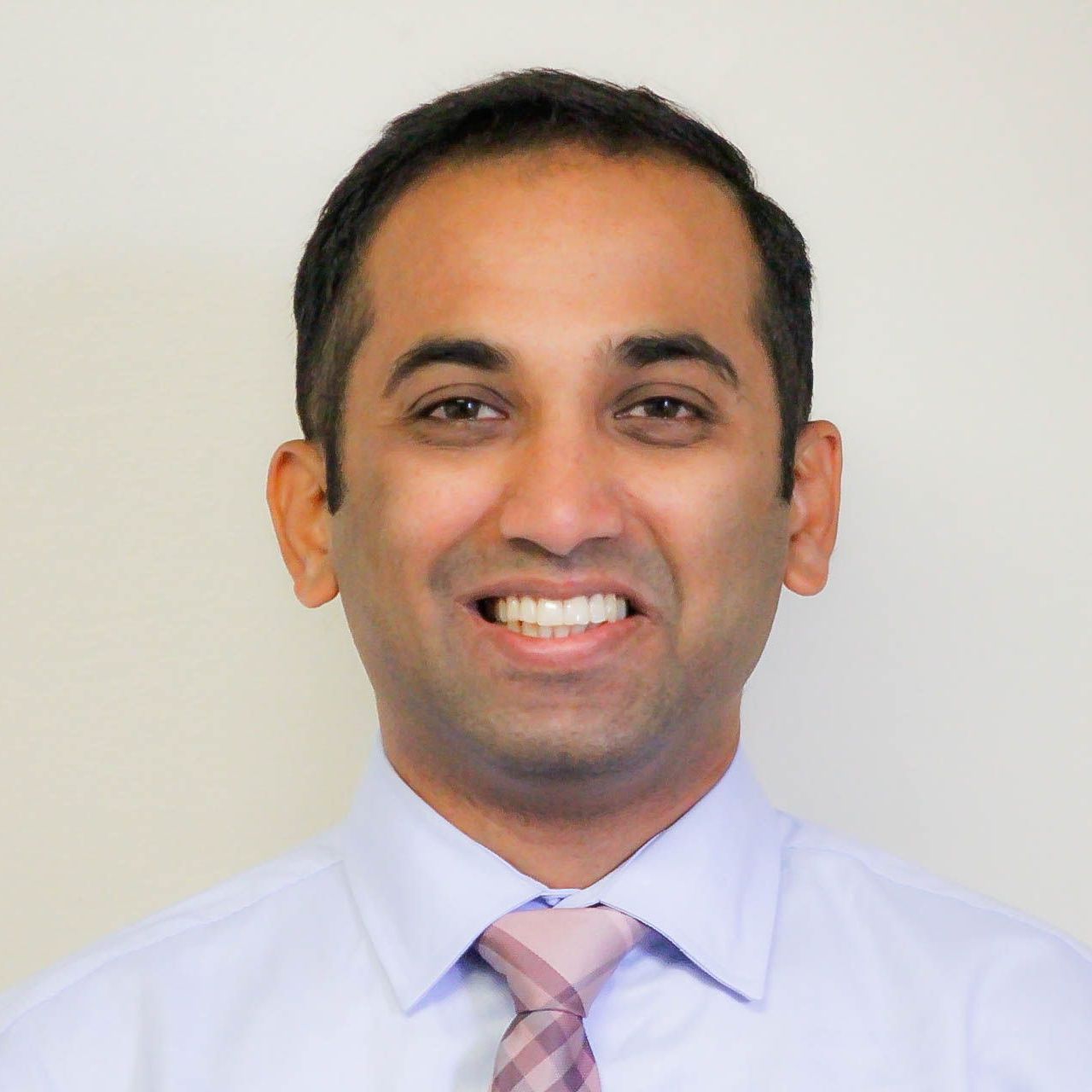 A man in a blue shirt and tie is smiling for the camera.