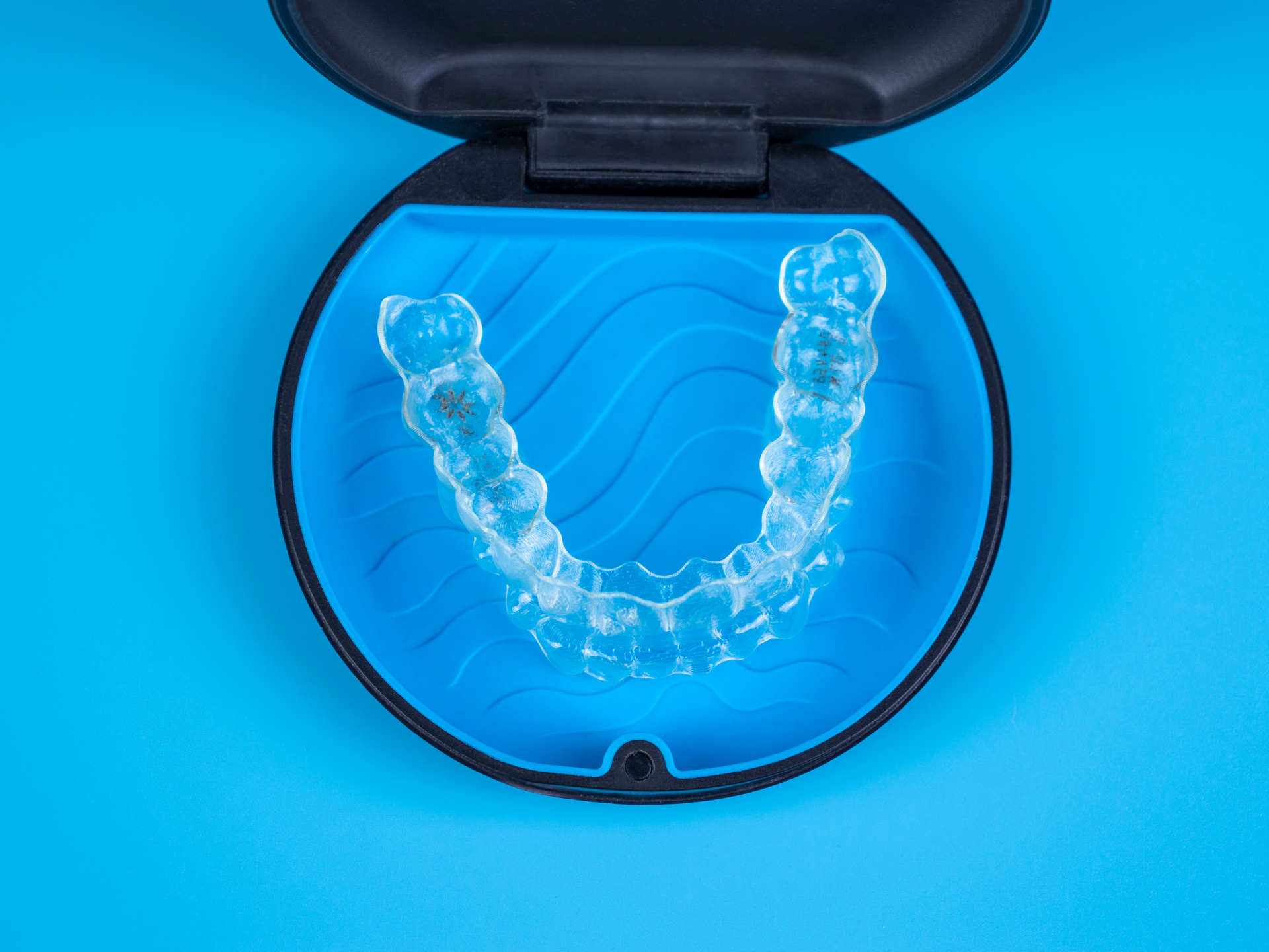 a pair of clear braces in a case on a blue surface .