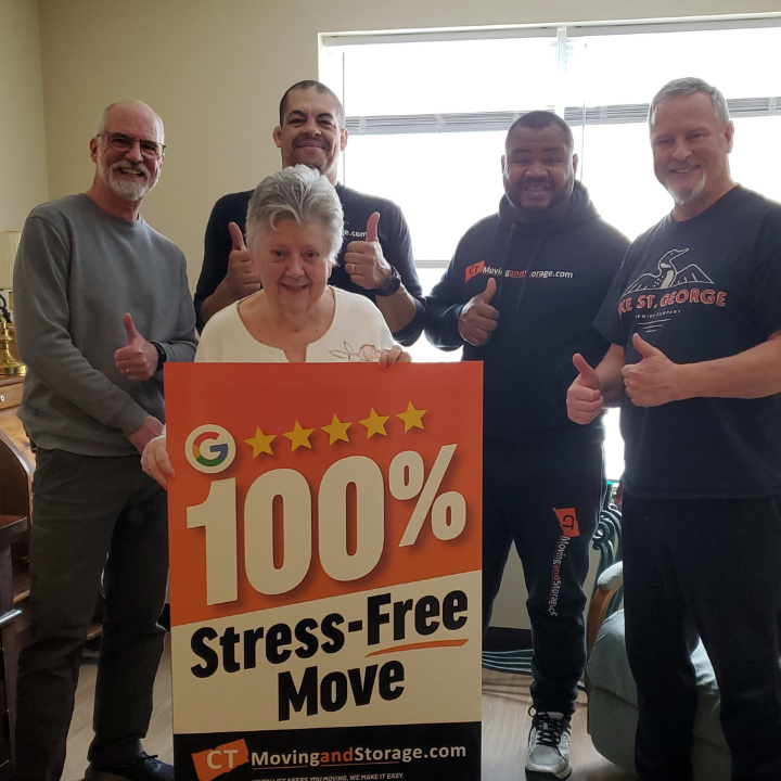 Five people with thumbs up, smiling, holding a sign for