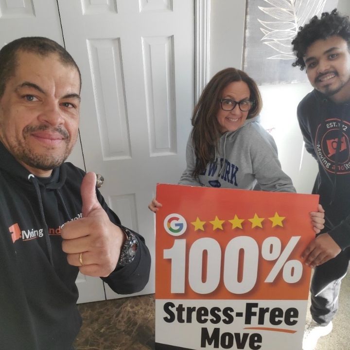 Three movers posing indoors with a “100% Stress-Free Move” sign, one giving a thumbs-up.
