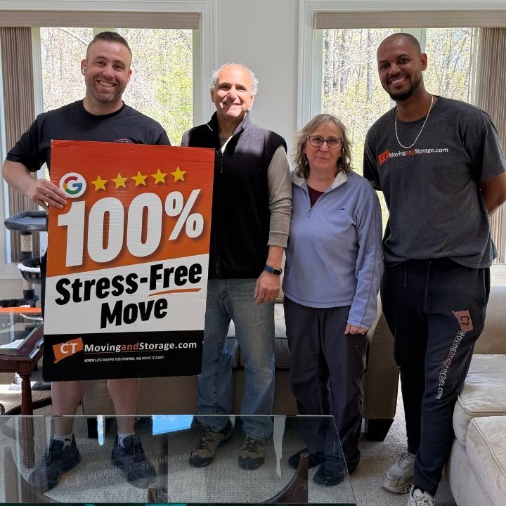 Four people in a room holding a “100% Stress-Free Move” sign