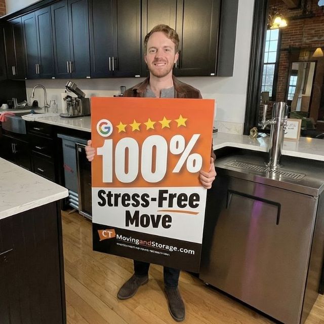 Man smiling, holding sign. Sign reads 