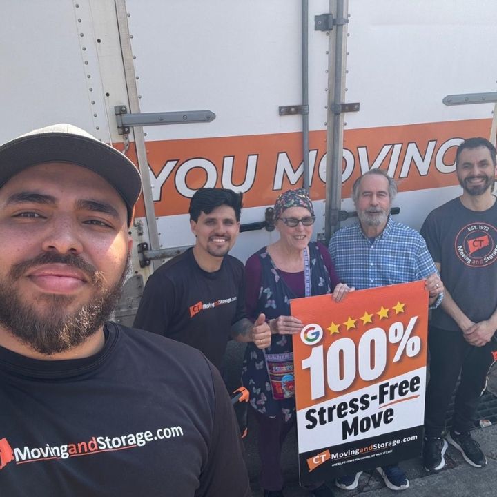 People posing with a “100% Stress-Free Move” sign in front of a moving truck.