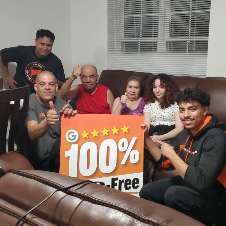 Group on a couch holding a large orange “100% Free” sign in a living room