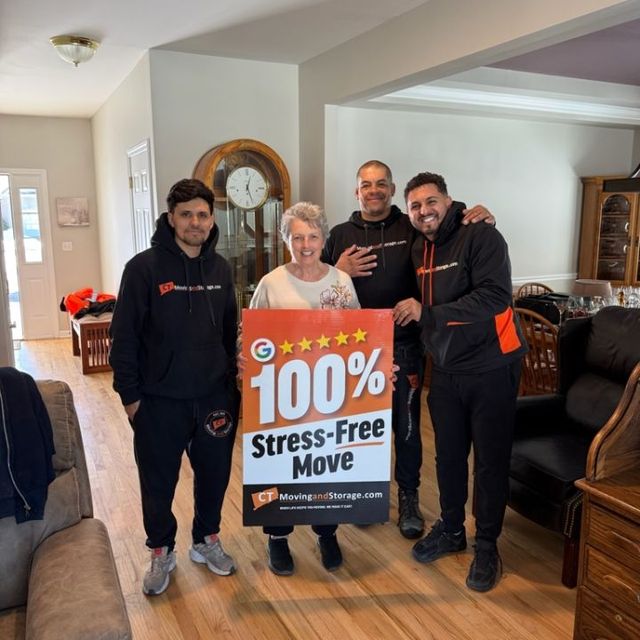 Four people, including a smiling woman, pose with a sign advertising a 