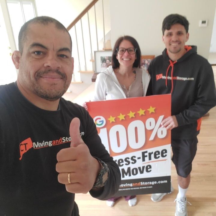 Three people indoors holding a “100% stress-free move” sign, one giving a thumbs-up.