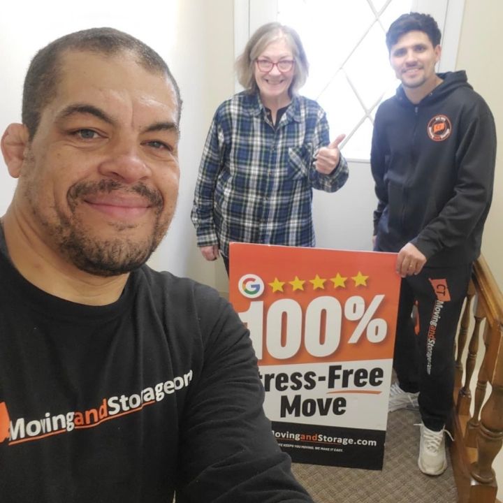 Three people posing indoors with a 100% stress-free move sign.