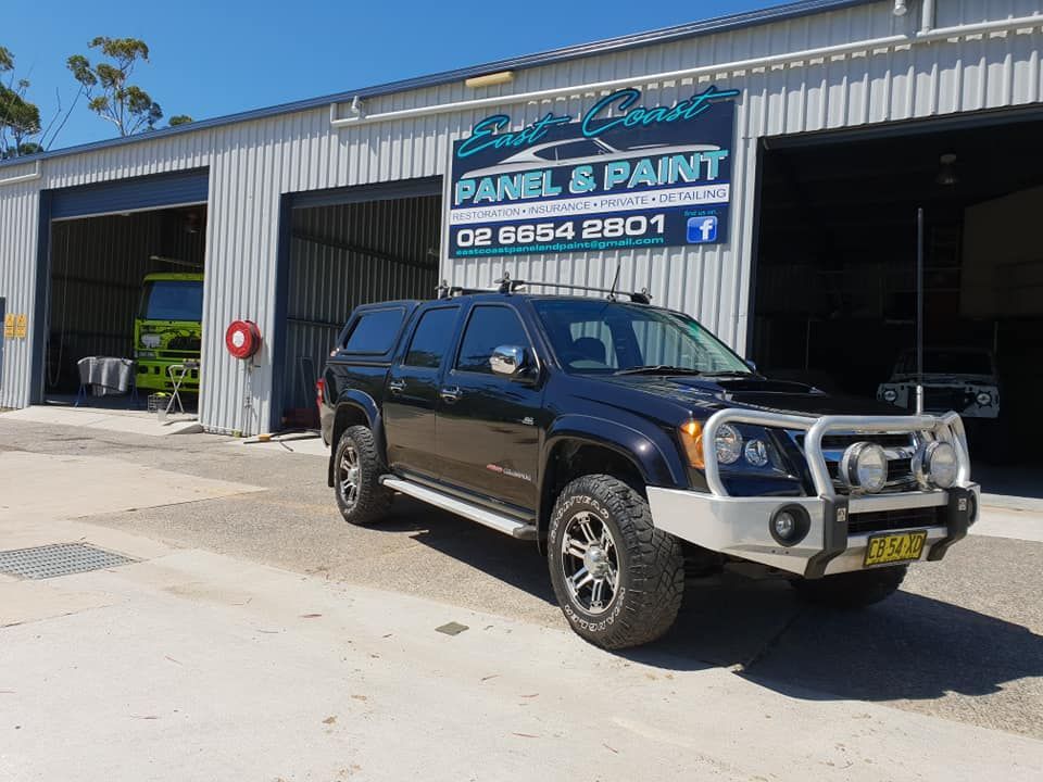 A Black Suv Is Parked In Front Of A Building That Says Panel & Paint — East Coast Panel & Paint In Woolgoolga, NSW