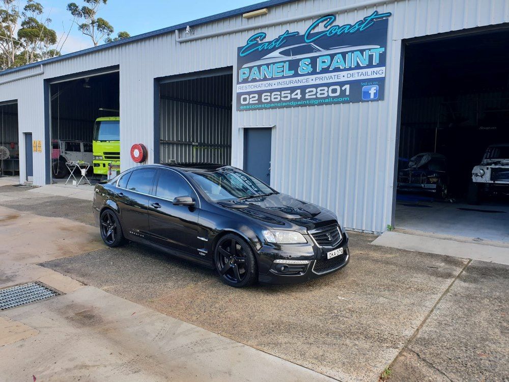 A Black Car Is Parked In Front Of A Garage — East Coast Panel & Paint In Woolgoolga, NSW