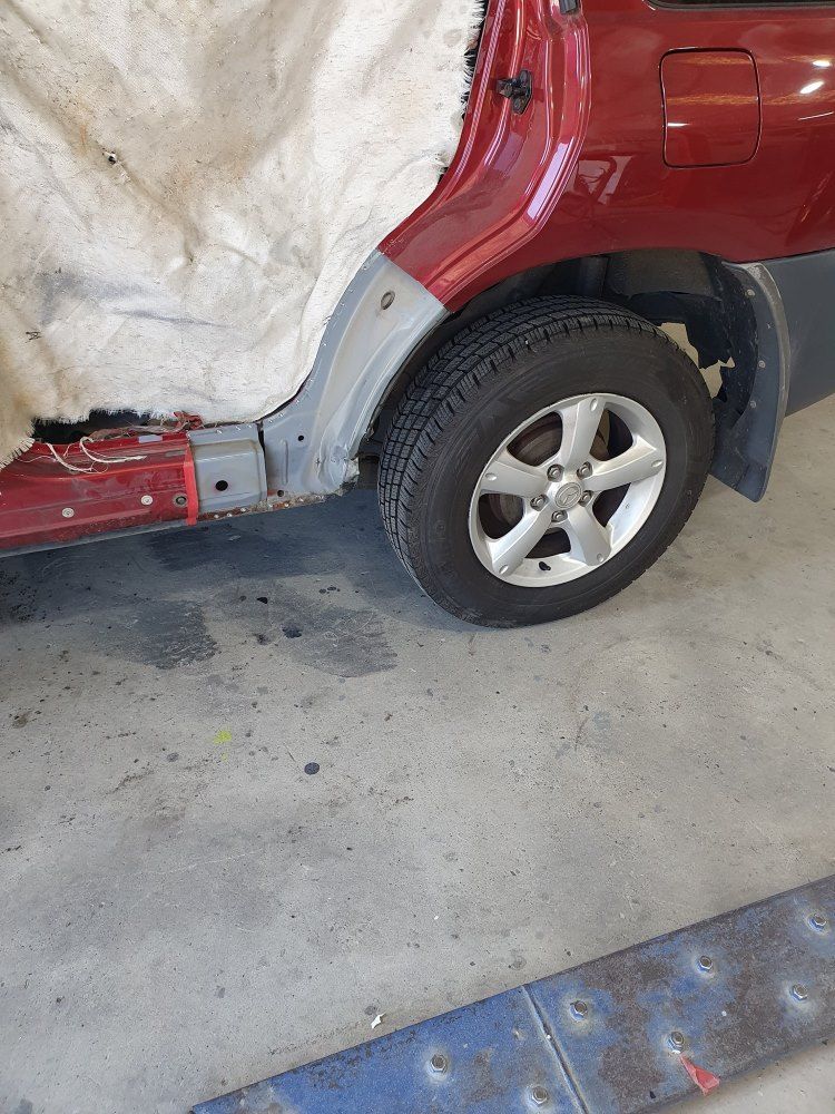 A Red Car Is Sitting On A Concrete Floor In A Garage — East Coast Panel & Paint In Woolgoolga, NSW