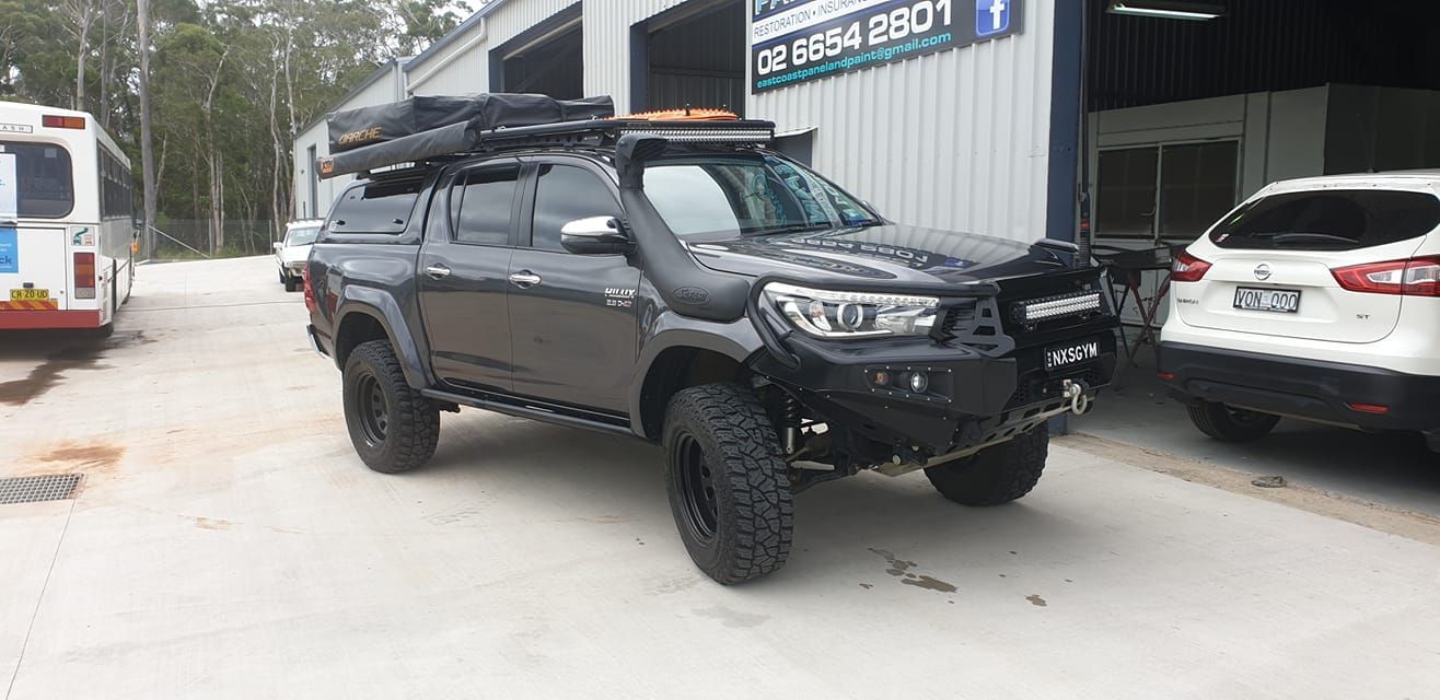 A Black Truck With A Tent On Top Of It Is Parked In Front Of A Building — East Coast Panel & Paint In Woolgoolga, NSW