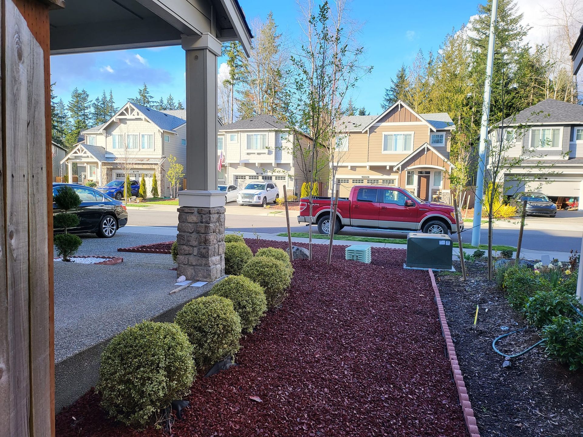 View of suburban homes with landscaping and a red truck parked in the street.