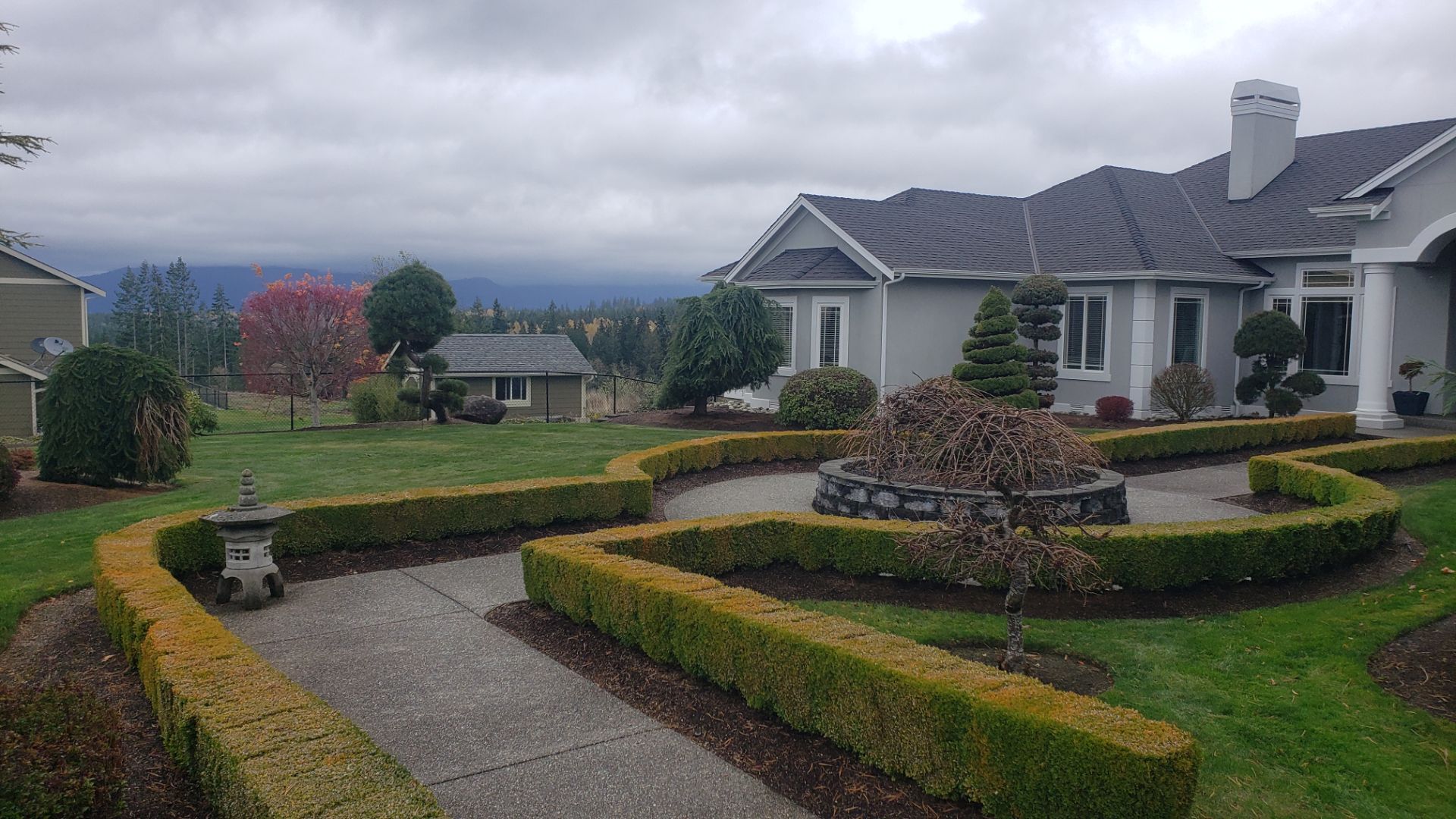 A house with manicured hedges and a winding pathway under a cloudy sky.