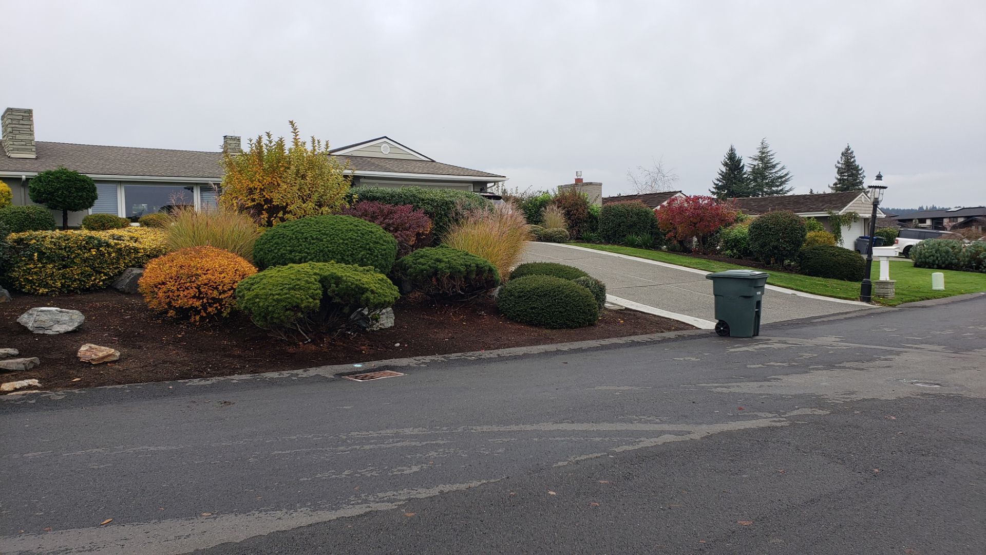 House with colorful landscaping and driveway, cloudy sky.