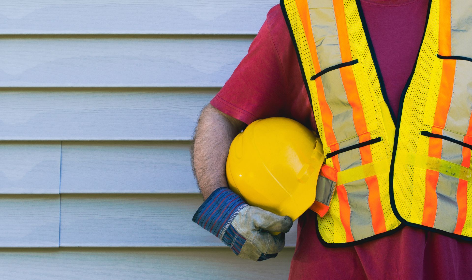 A construction worker is working on the siding of a house.