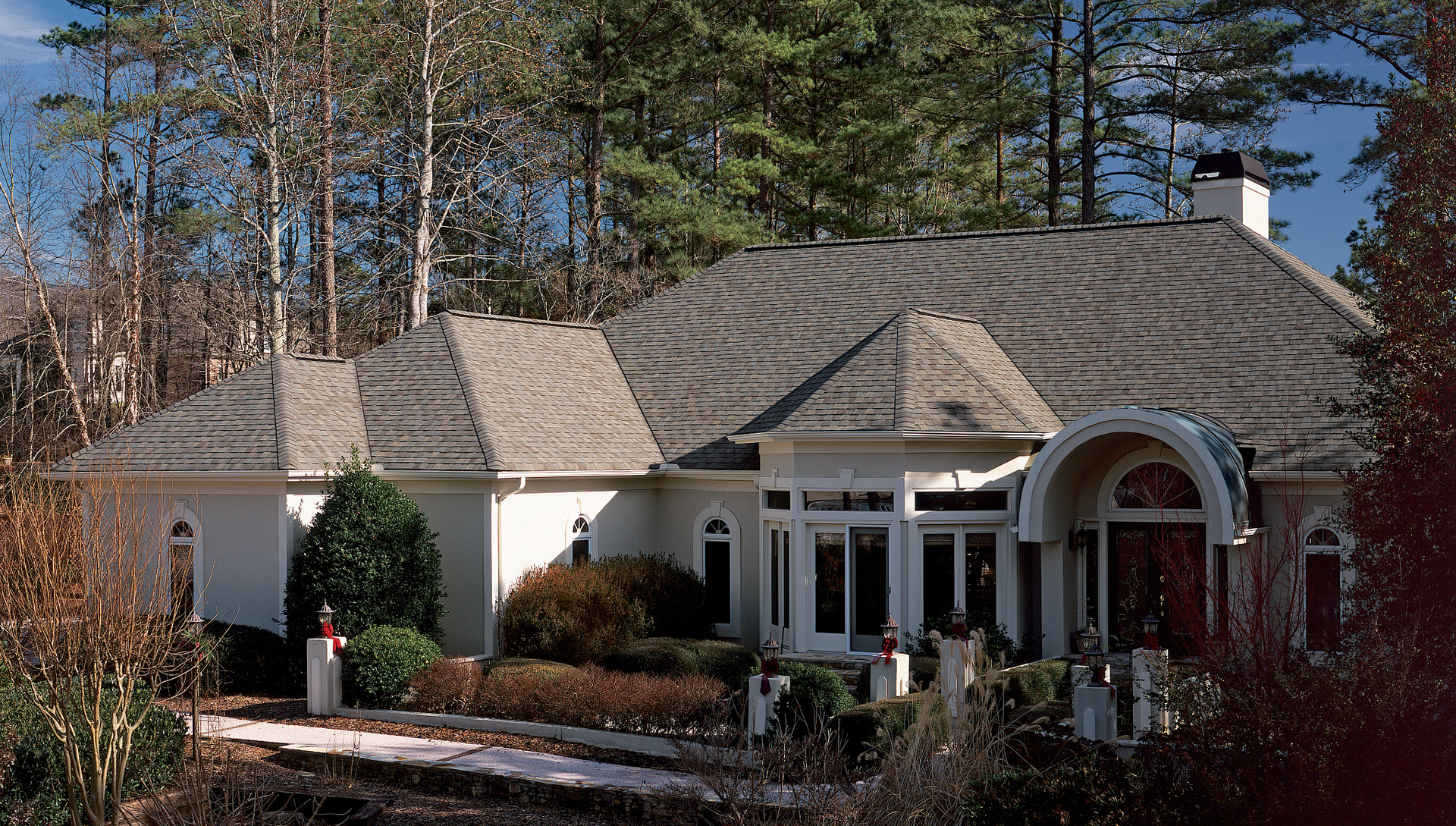 A large white house is surrounded by trees on a sunny day