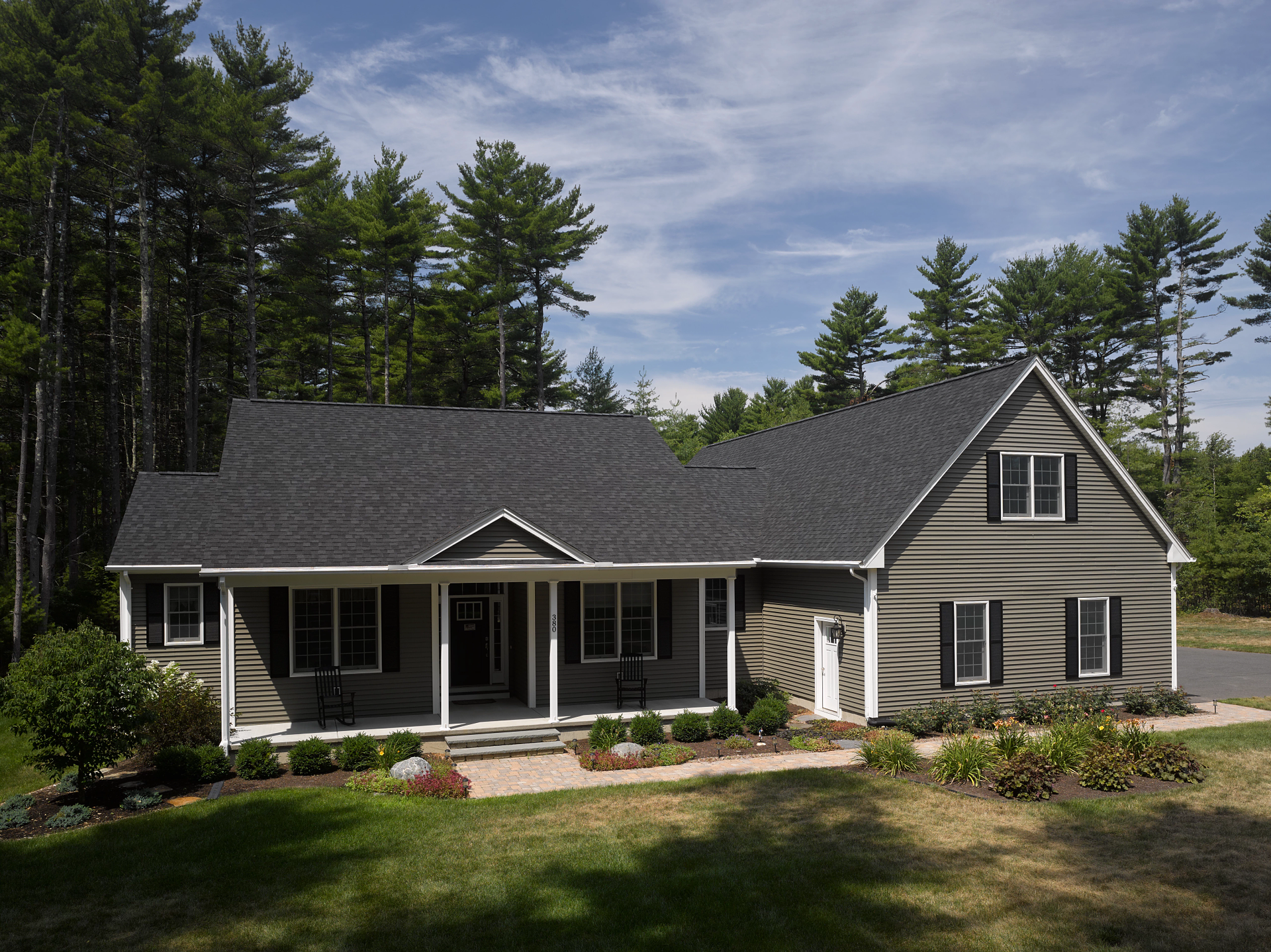 A house with a large porch is surrounded by trees