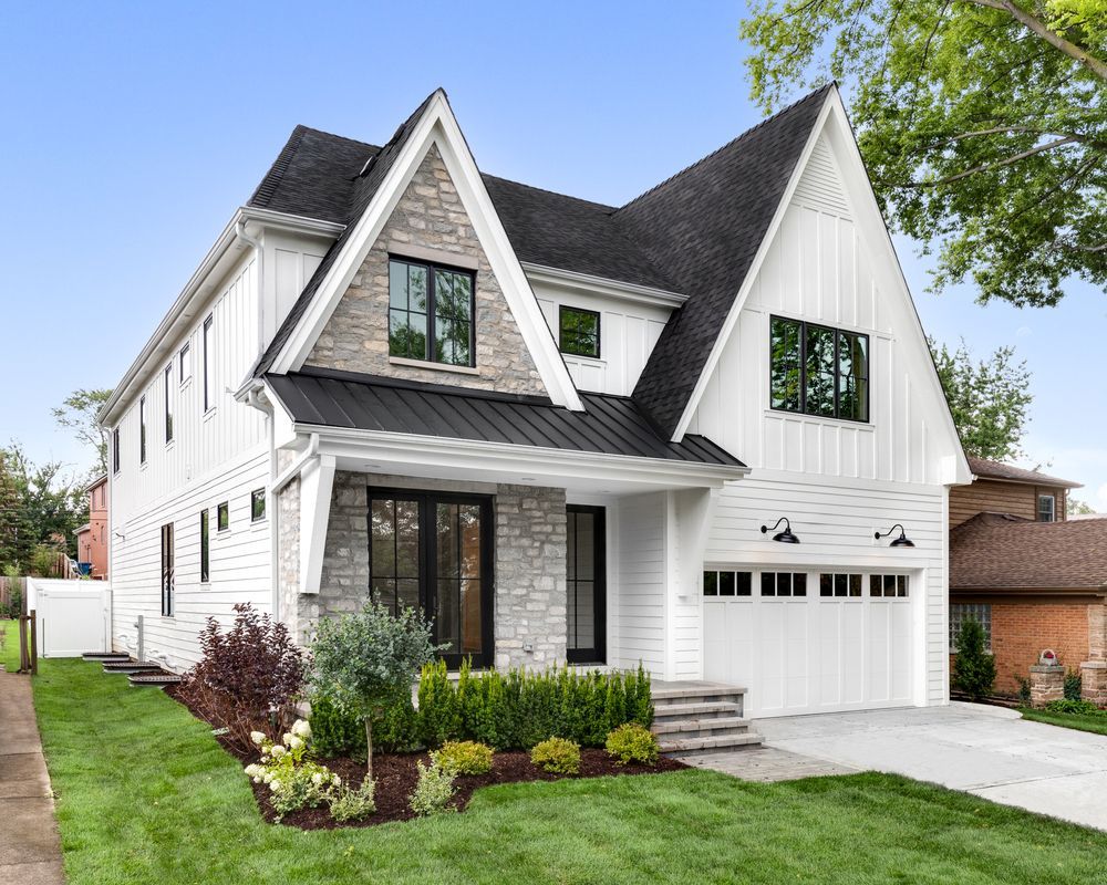 A white house with a black roof and a black garage door.