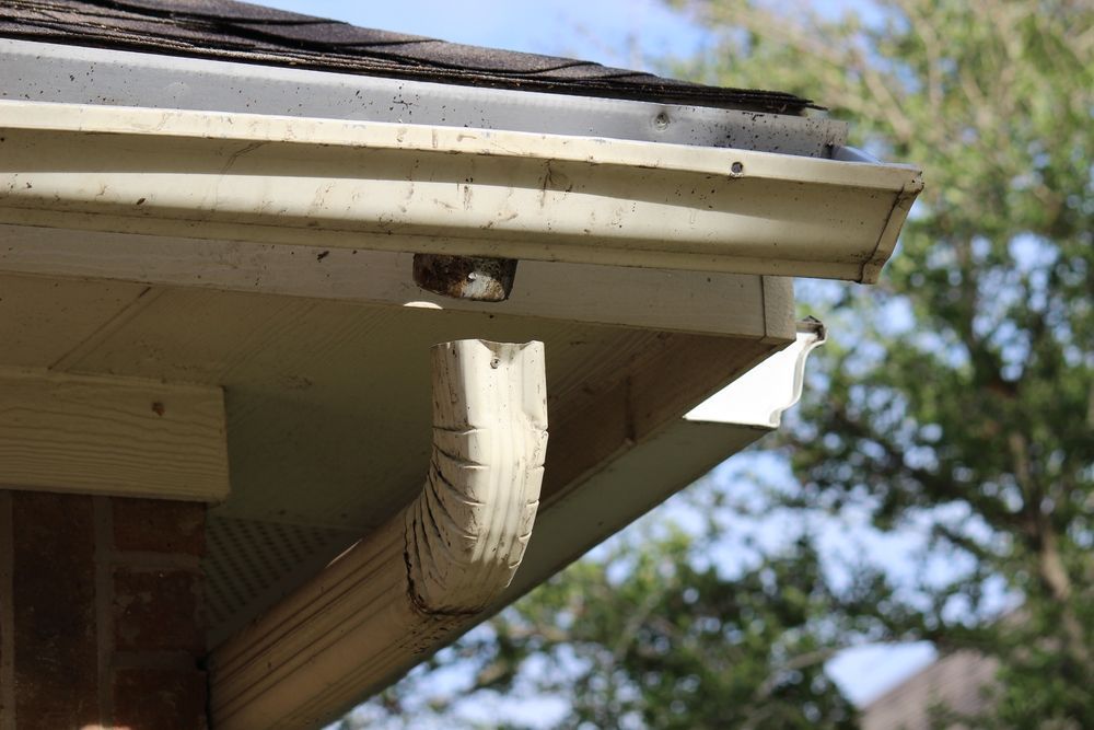 A close up of a gutter on the side of a house.