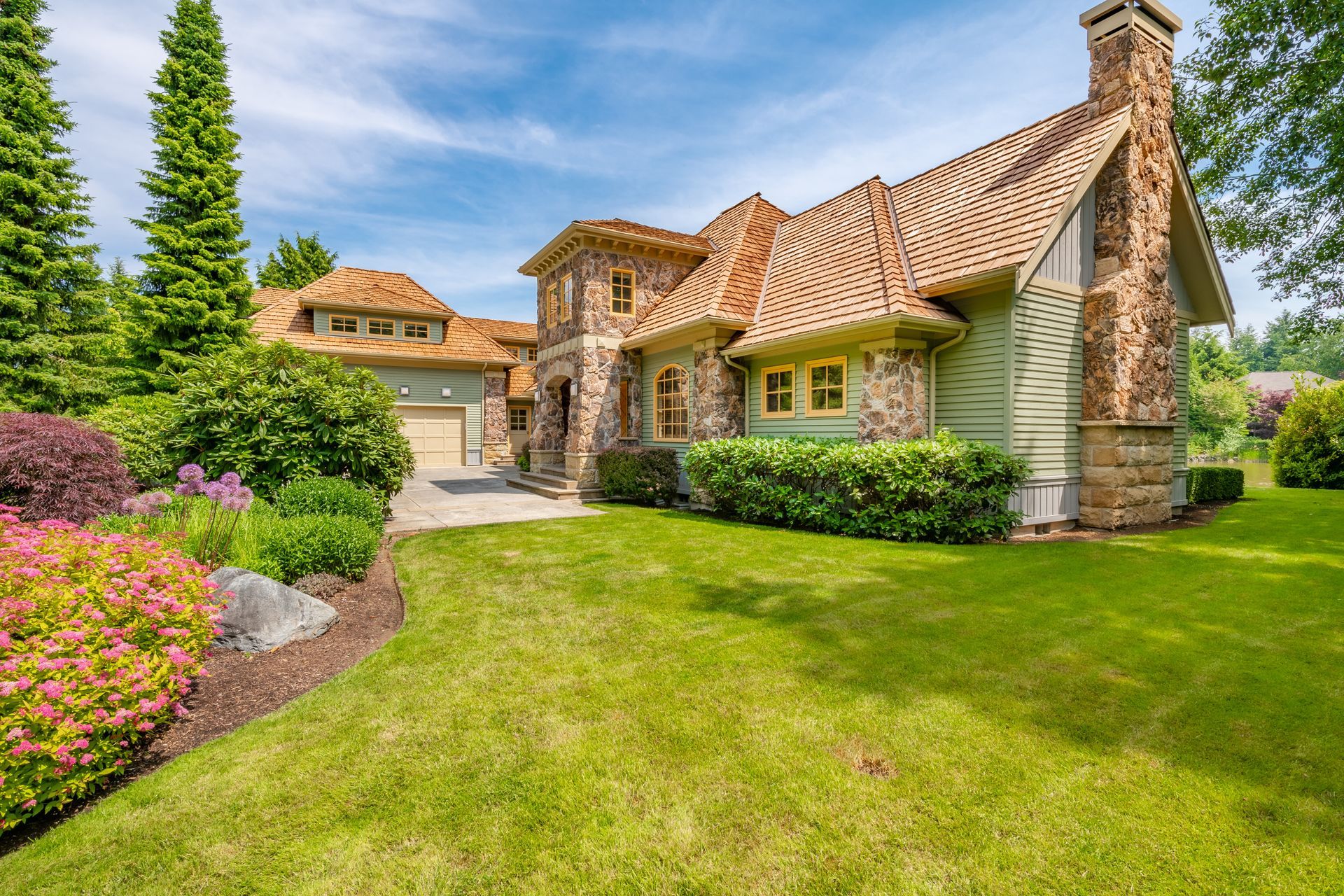 A large house with a lot of grass and flowers in front of it.