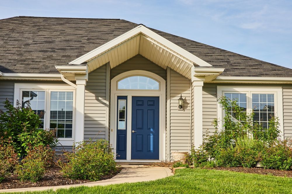 The front of a house with a blue door and a walkway leading to it.