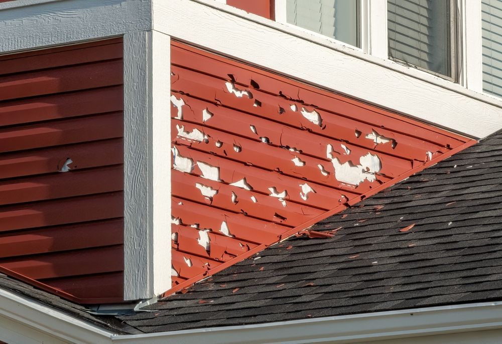 damaged red vinyl siding on a home that needs to be repaired or replaced