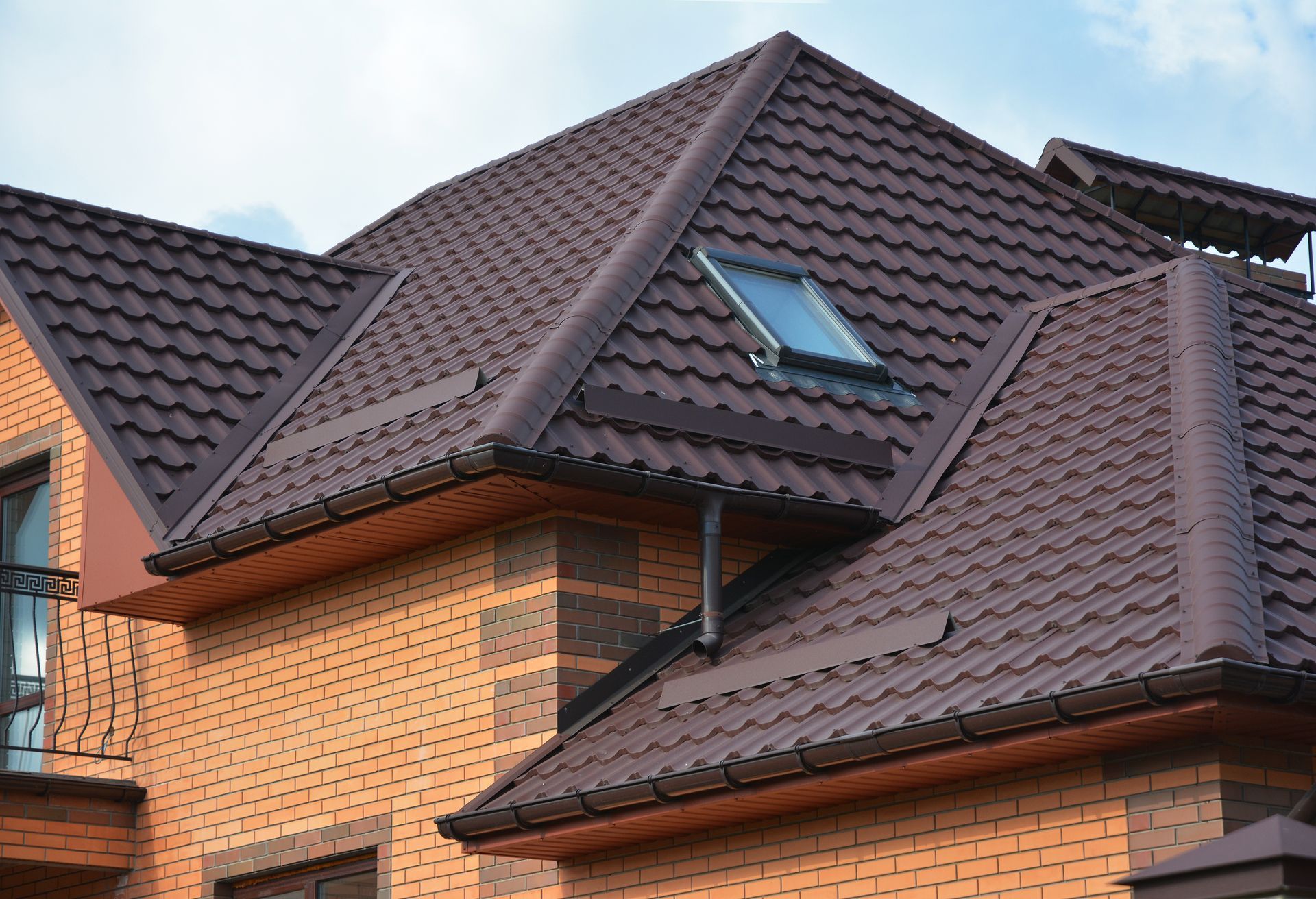 A brick house with a brown roof and a skylight on the roof.