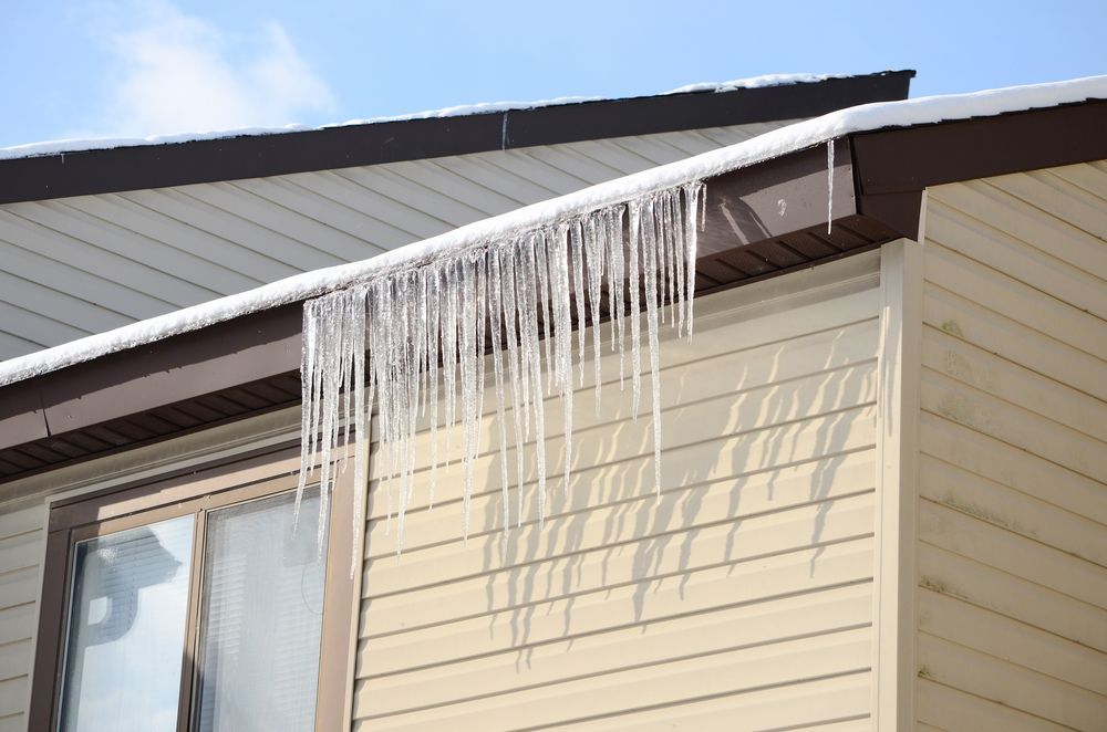 Icicles are hanging from the roof of a house.