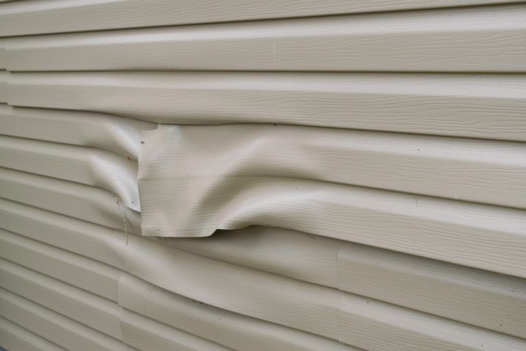 A close up of a damaged siding on a house.