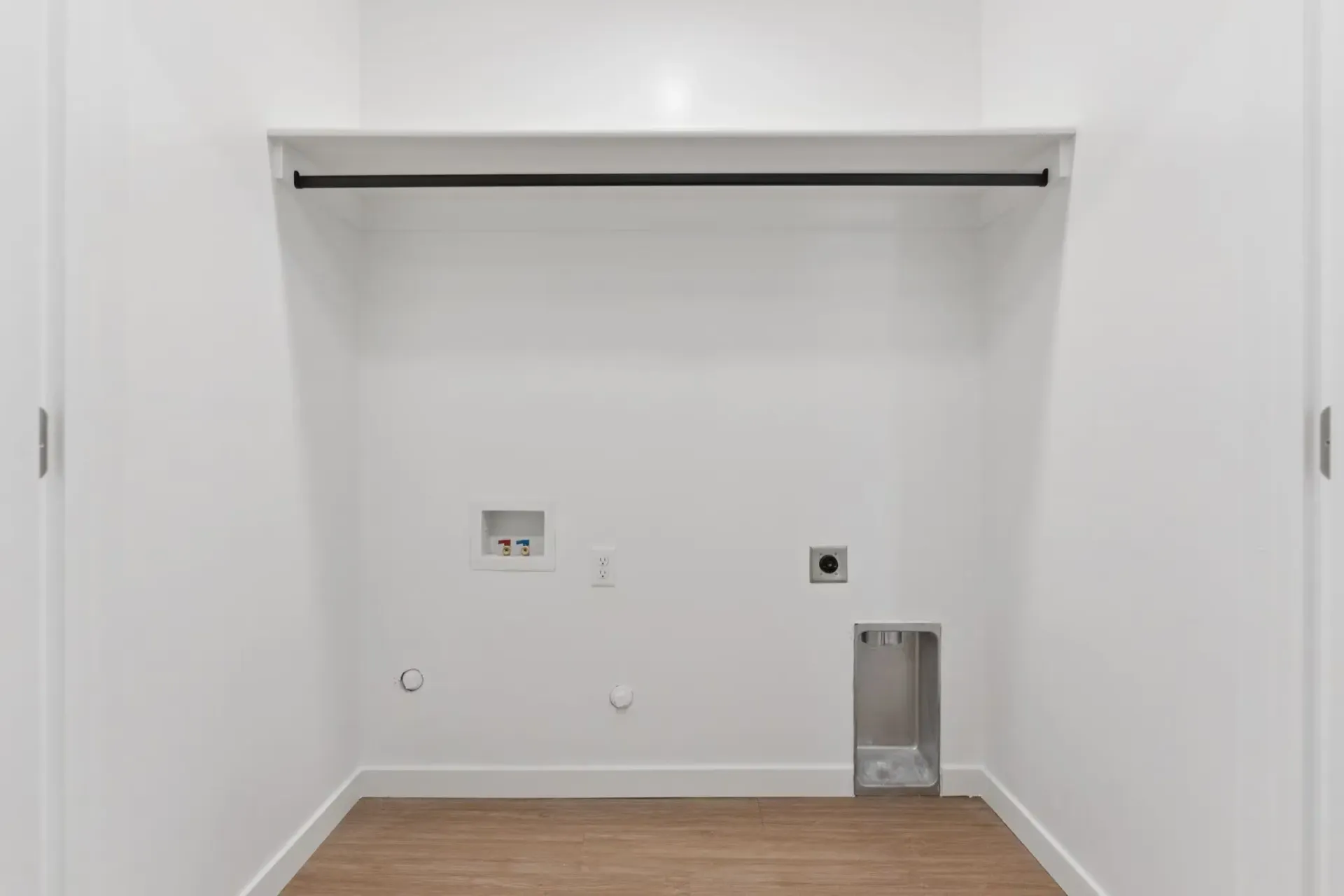 Laundry closet with rod, washer/dryer hookups, outlet, and drain pan.