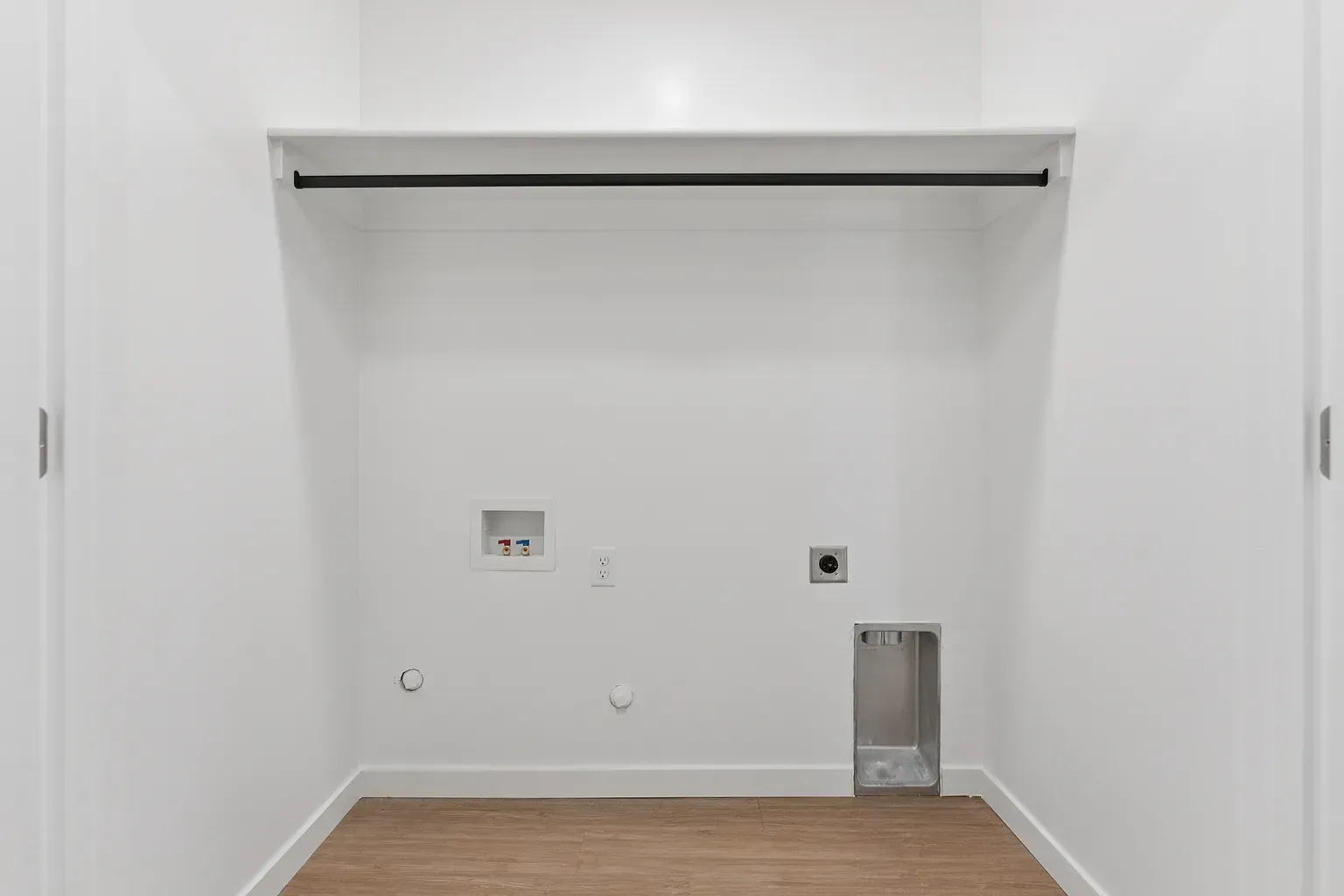 Laundry closet with hanging rod and washer/dryer hookups.