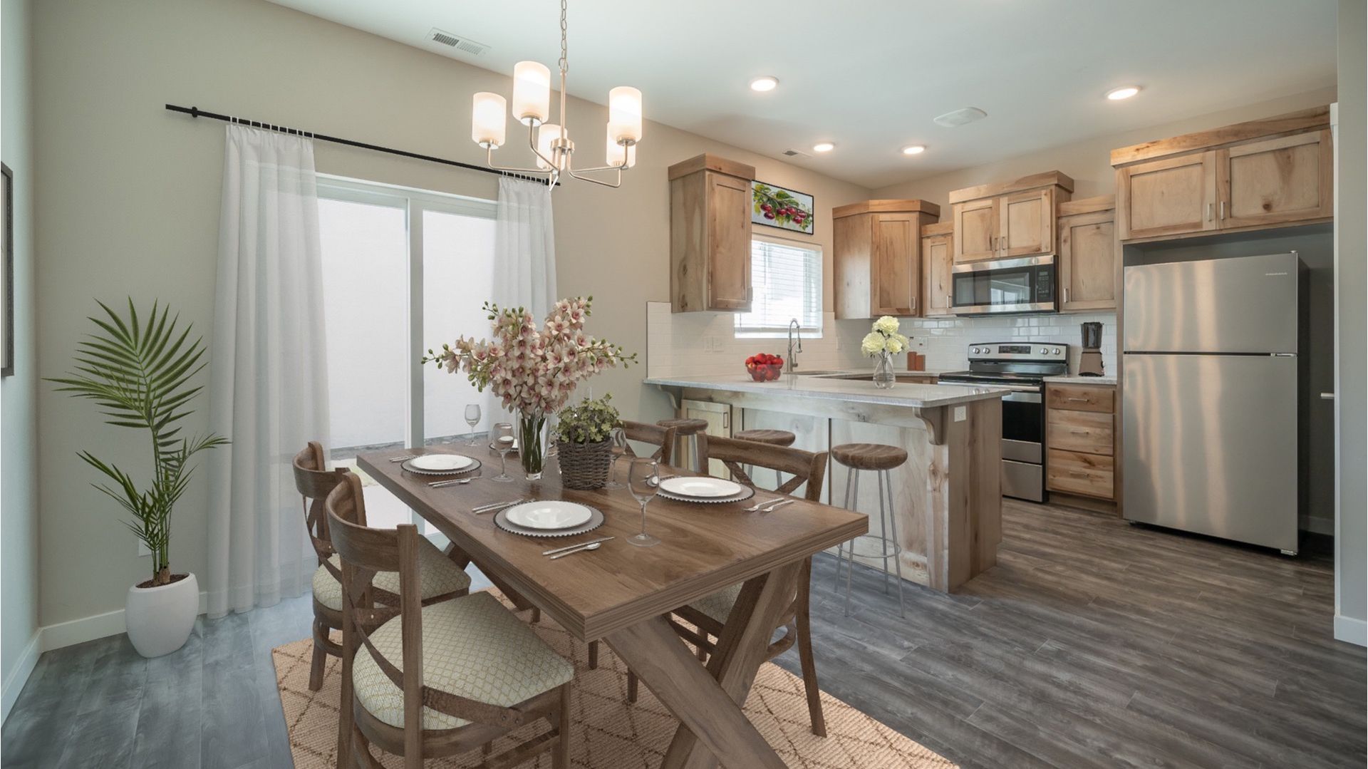 Interior dining area with a wooden table, chairs, and a kitchen island with stainless appliances.
