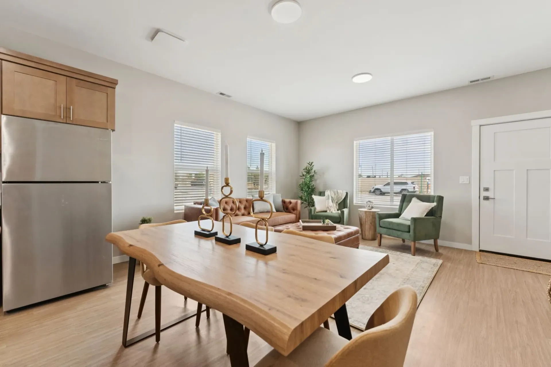 Open-concept living area with a wooden dining table, stainless steel fridge, and casual seating.