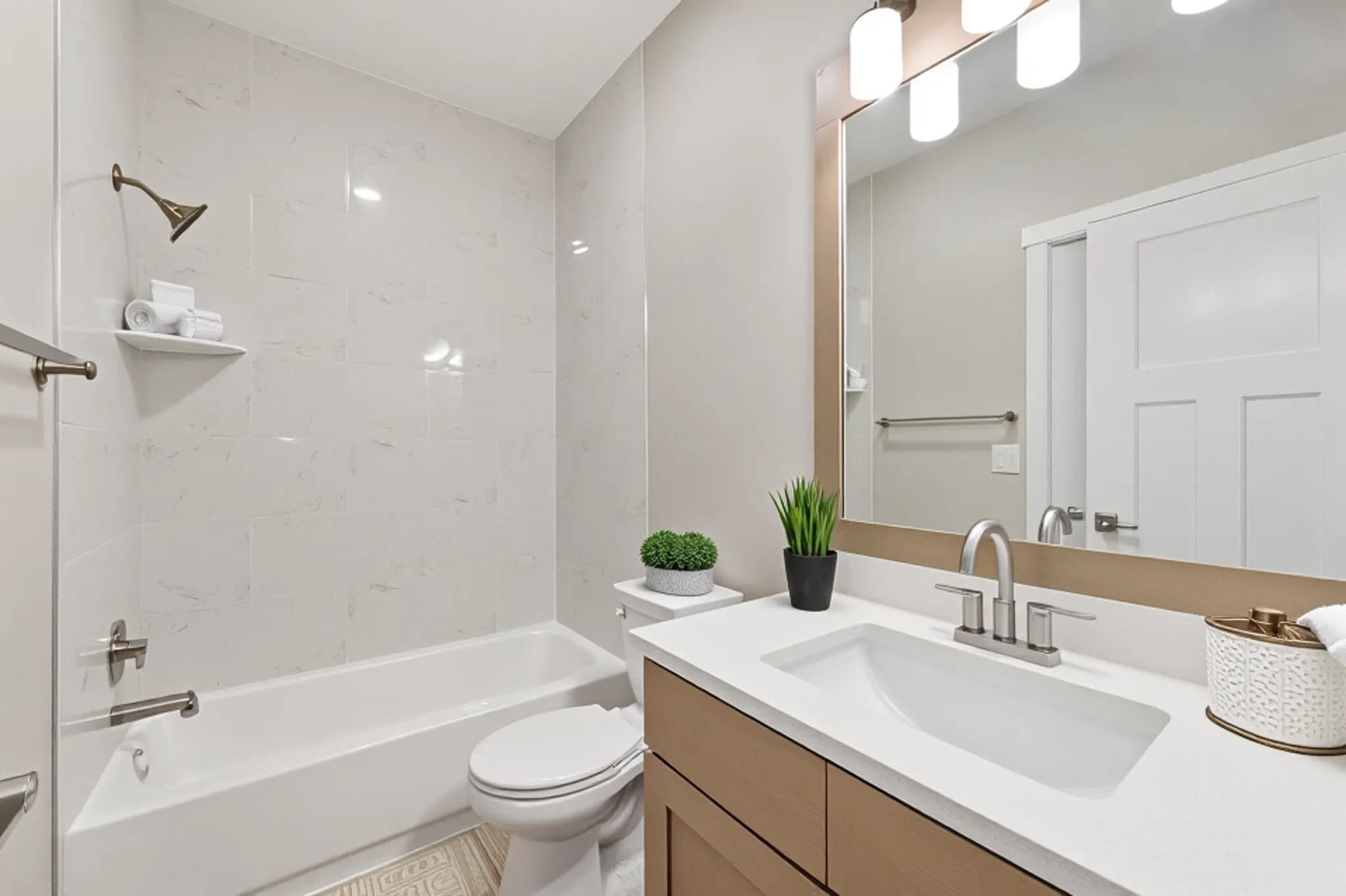 Modern bathroom with a vanity, sink, toilet, and tub/shower.