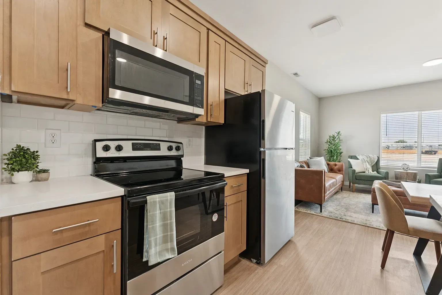 Apartment kitchen with wood cabinets, stainless steel stove, microwave, and refrigerator.