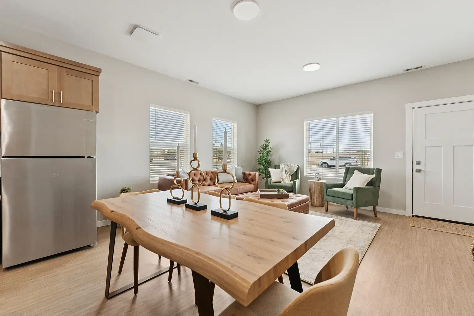 Open-concept living area with dining table, sofa, chairs, and a stainless fridge.