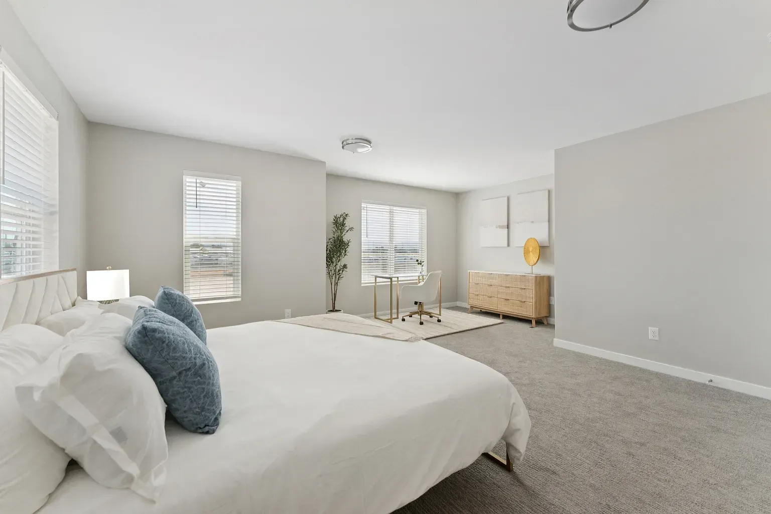 Bright, modern bedroom with a white bed, windows, desk, and dresser.