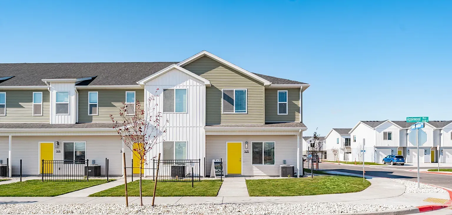 Exterior view of a multi-family community with townhouse-style units and yellow doors.