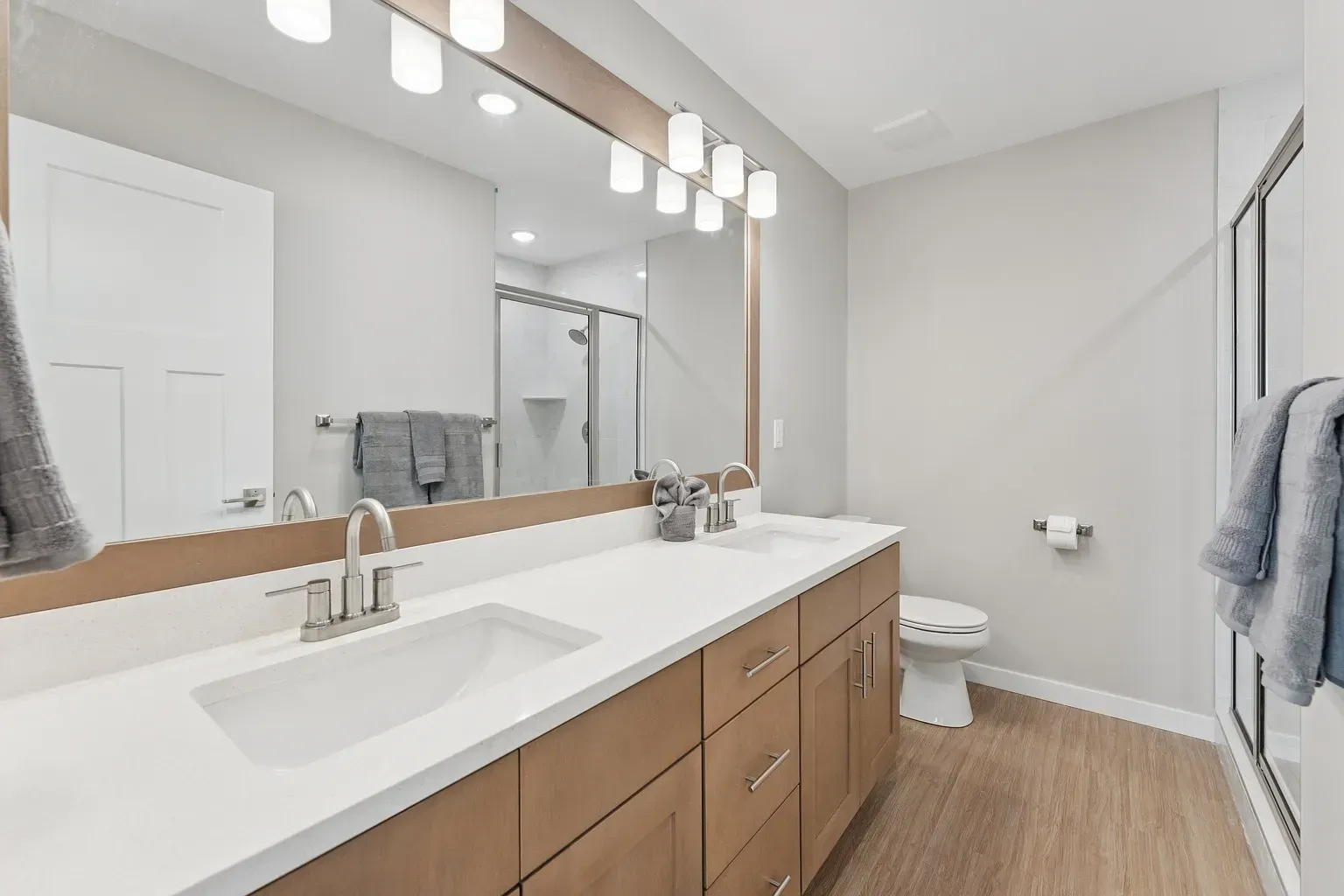 Modern bathroom with a double vanity, large mirror, and glass shower.