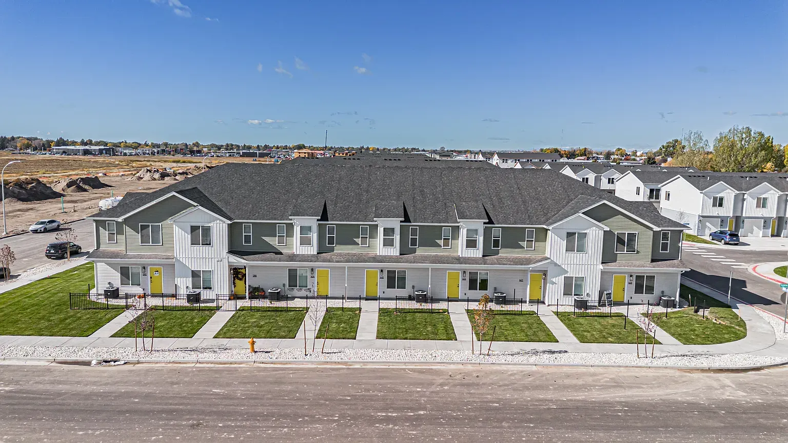 Row of townhouse-style apartment buildings with green/white siding and yellow doors.