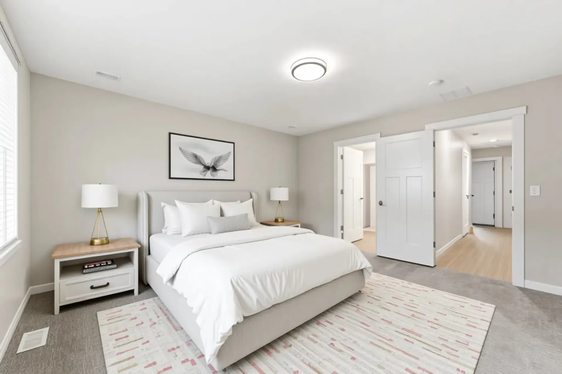 Modern apartment bedroom with a white bed, two nightstands, and an open doorway to the hallway.