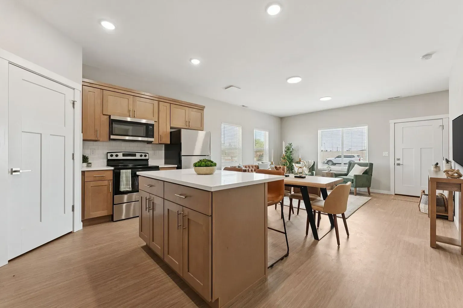 Open-concept kitchen and living area with an island, dining table, and windows.