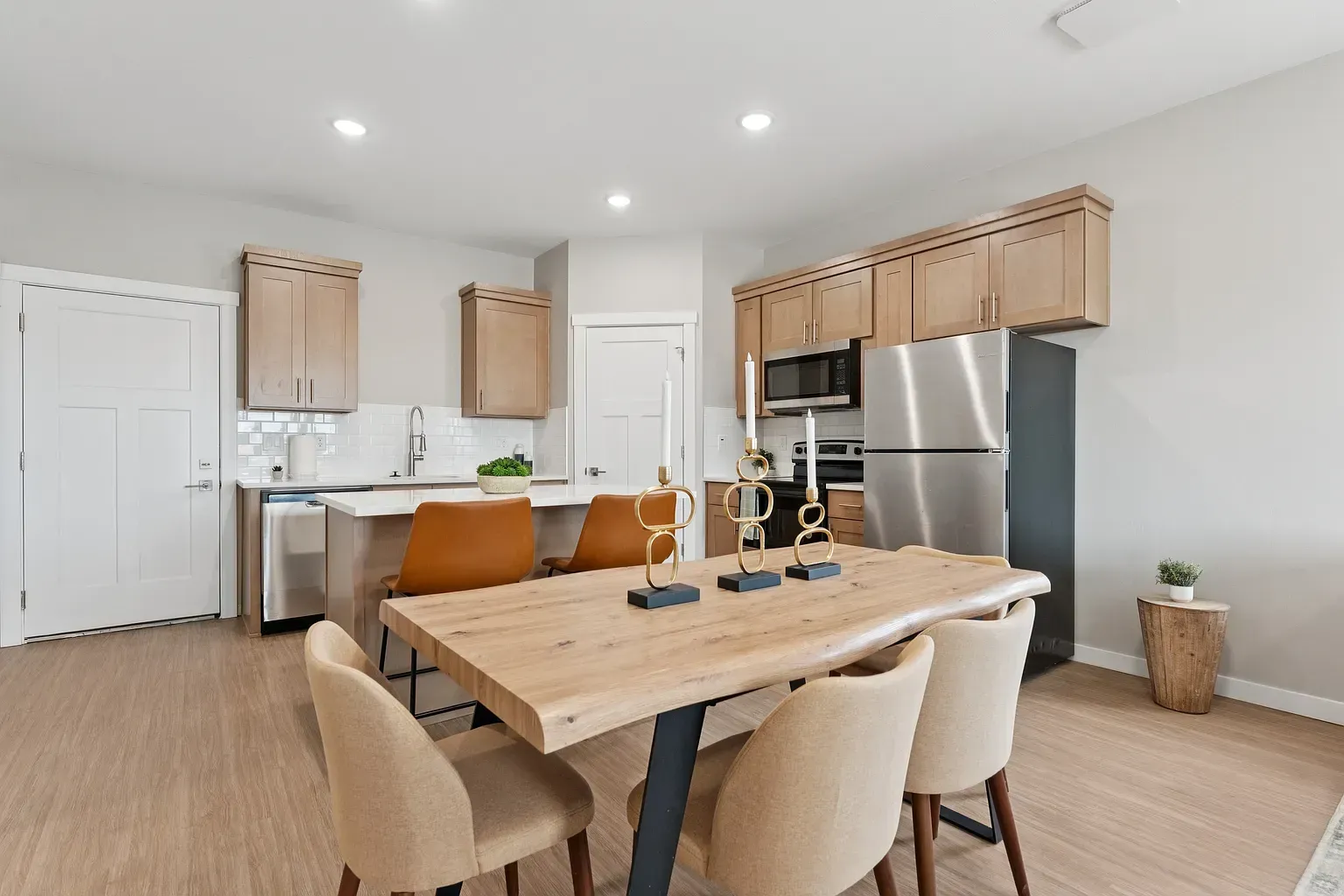 Open-concept kitchen with island, wood cabinets, stainless-steel appliances, and a dining table with chairs.