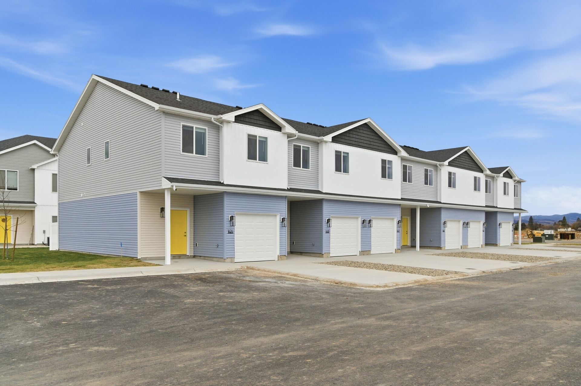 Row of modern two-story townhomes with attached garages under a blue sky.