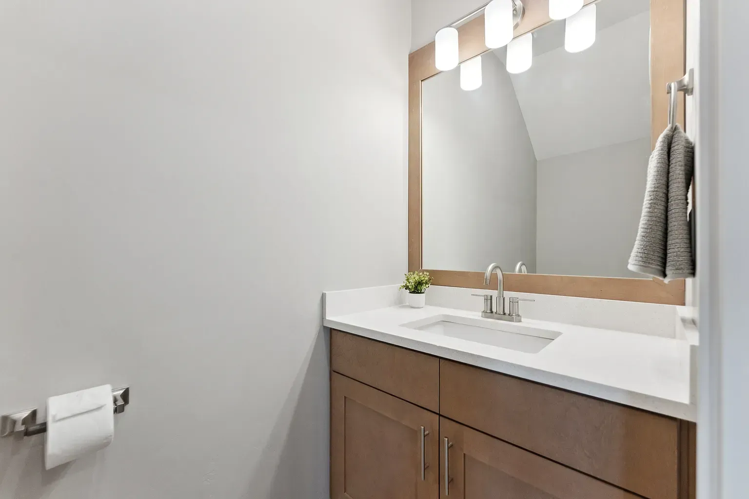 Bathroom vanity with wood cabinetry, white countertop, sink, and framed mirror.
