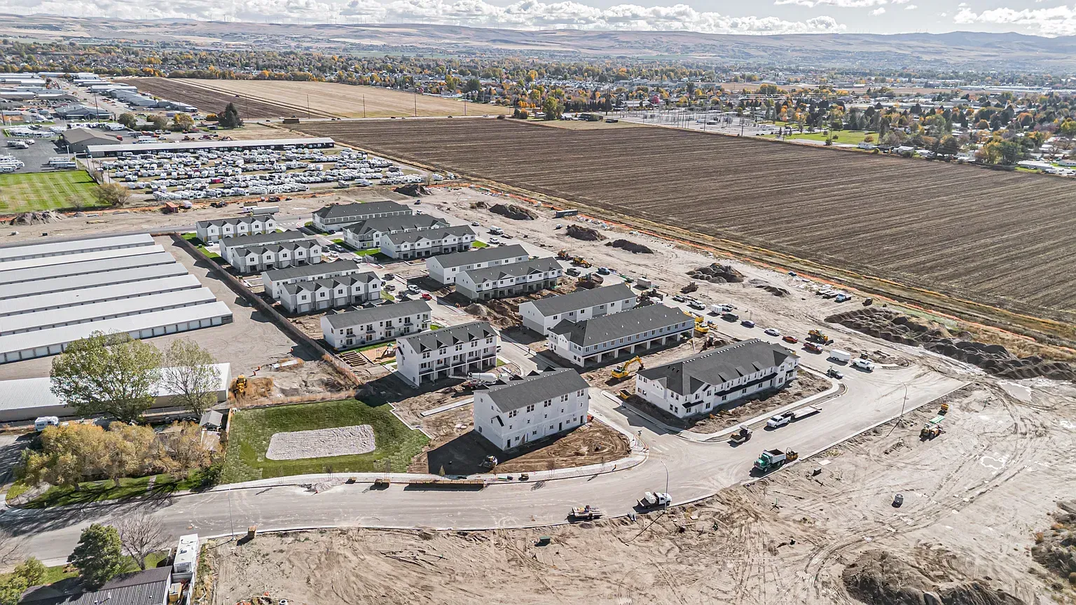 Aerial view of a developing multifamily community with white residential buildings and construction sites.